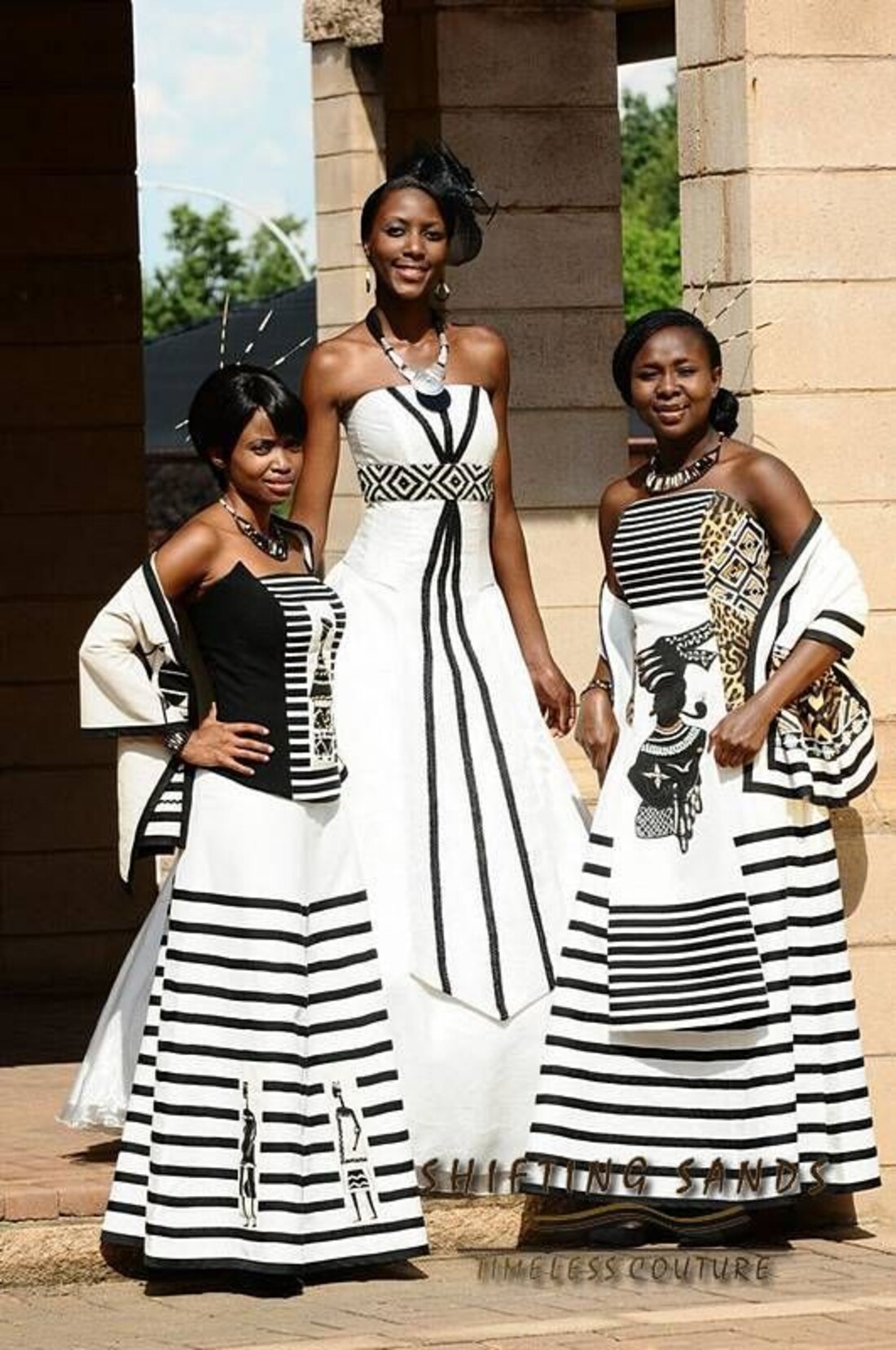 Three women in black and white striped traditional attire